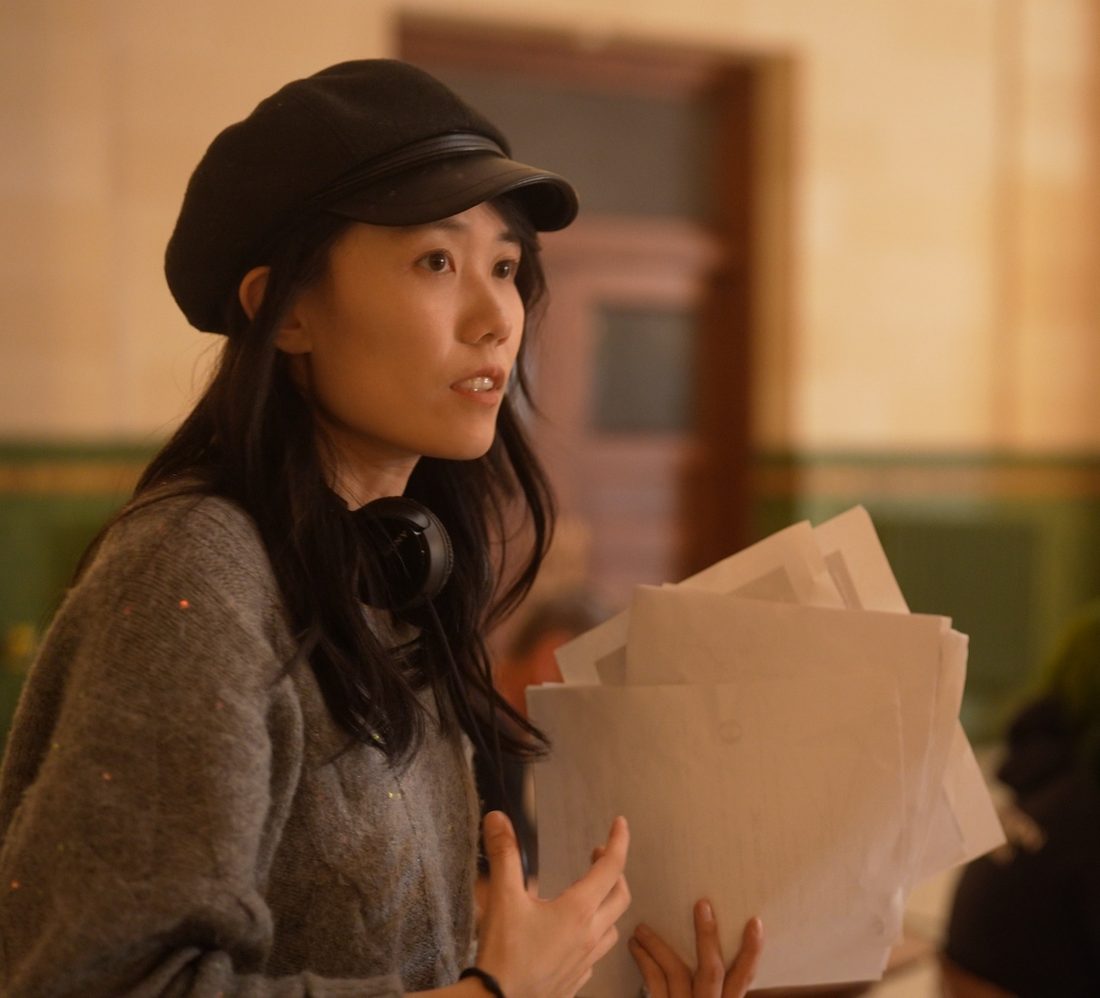 Yuyao Zhong directing on set in Union Station, holding a stack of script pages